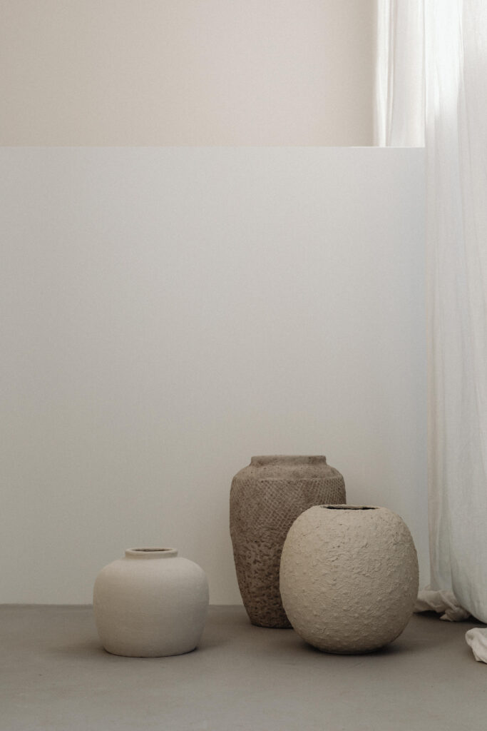 Handmade ceramic vessels against light coloured walls and curtains